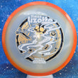 Load image into Gallery viewer, Top-down view of an Axiom Aspect fairway driver disc golf disc in Eclipse Glow plastic with an orange overmold rim and a black, white, and gold holographic foil Simon Lizotte Halloween Tour Series stamp.
