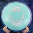 Load image into Gallery viewer, Top-down view of a light teal Axiom Defy distance driver disc golf disc in Fission plastic with a blue and pink GYRO overmold rim and silver foil stock Defy stamp.
