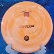 Load image into Gallery viewer, Top-down view of an orange and white swirled Discmania Drop approach disc golf disc in Swirl S-Line plastic with an orange holographic foil Niklas Anttila Creator Series stamp.
