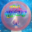 Load image into Gallery viewer, A translucent pink Discraft Vulture golf disc with a holographic rainbow foil decal reading 'Get Sneaky' and a blue Vulture logo, shown against a blue starry background.
