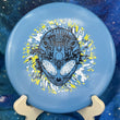 Load image into Gallery viewer, Top-down view of a light blue Infinite Discs Cohort putt and approach disc golf disc in I-Blend plastic with a black, white, and yellow three-foil Neon Alien Head stamp.
