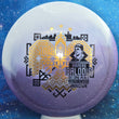 Load image into Gallery viewer, Top-down view of an Innova Teebird Rainers Balodis Commemorative fairway driver in white and purple Duo Star plastic with black and gold holo foil stamp scaled at 174g.
