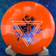 Load image into Gallery viewer, Top-down view of an orange Innova XCaliber distance driver disc golf disc in Star plastic featuring a white and blue dual-foil Neon Astro special edition stamp.
