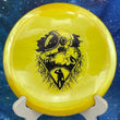 Load image into Gallery viewer, Top-down view of a brand-new metallic yellow Mint Discs Alpha fairway driver disc golf disc in Sublime plastic with a black foil Unearthed serial run SB-AL07-24 graphic stamp.
