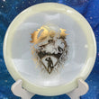 Load image into Gallery viewer, Top-down view of a glow Mint Discs Phoenix fairway driver disc golf disc in Nocturnal Glow plastic featuring a gold foil Unearthed special edition stamp.
