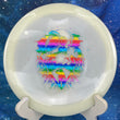 Load image into Gallery viewer, Top-down view of a glow Mint Discs Phoenix fairway driver disc golf disc in Nocturnal Glow plastic featuring a rainbow foil Unearthed special edition stamp.
