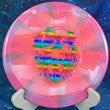 Load image into Gallery viewer, Top-down view of a pink, light purple, and teal swirl Mint Discs Phoenix fairway driver disc golf disc in Apex Swirl plastic featuring a foil Unearthed special edition stamp.
