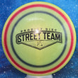 Load image into Gallery viewer, Top-down view of a pre-owned neon yellow, red, and black Prodigy A3 overstable approach disc golf disc in 500 Glimmer plastic featuring a Street Team stamp scaled at 174g in 9.5 out of 10 uninked condition.
