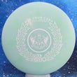 Load image into Gallery viewer, Top-down view of a pre-owned teal 2018 Glass Blown Open Truly Unique Dynamic Discs Deputy putter disc golf disc in Classic Blend Burst plastic scaled at 174g in 10 out of 10 uninked condition.
