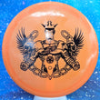 Load image into Gallery viewer, Top-down view of a pre-owned orange Zombie Trilogy Man stamped Dynamic Discs Justice midrange disc golf disc in Fuzion DyeMax plastic in 10 out of 10 uninked condition.

