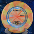Load image into Gallery viewer, Top-down view of a yellow and orange swirled Streamline Runway midrange disc golf disc in Cosmic Neutron plastic featuring a tri-foil stock Runway stamp.
