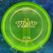 Load image into Gallery viewer, Top view of a Lime Green translucent Discraft Wasp disc in Z-Line plastic with a Digital Gold patterned stamp on a cosmic blue background.
