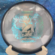 Load image into Gallery viewer, Top view of a Black Proto Glow Halo Champion Innova Emily Weatherman Fox midrange featuring a glowing core and a Purple Holo tri-foil champion series stamp, 178g, 10/10 condition.
