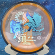 Load image into Gallery viewer, Orange Proton Resistor disc golf driver from the Eagle McMahon Synergy Series featuring a detailed blue and white eagle stamp.
